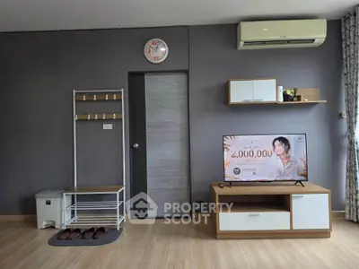 Modern living room with stylish furniture and wall-mounted air conditioner, featuring a sleek TV stand and wall clock.