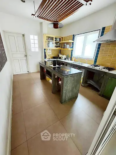 Modern kitchen with open layout and gas stove, featuring sleek countertops and ample natural light.