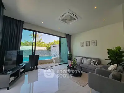 Luxurious living room with pool view, modern decor, and ample natural light.