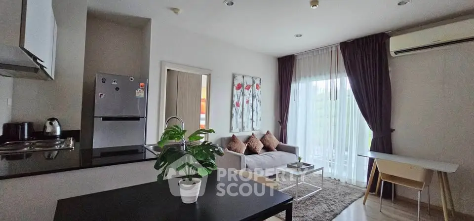 Modern open-layout living room with kitchen, featuring stylish decor and natural light.