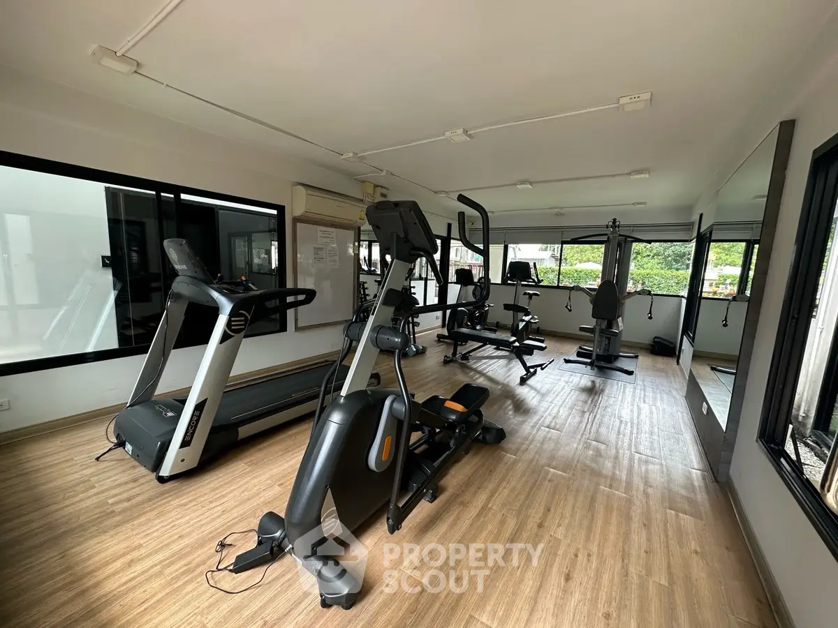 Modern gym with state-of-the-art equipment and large windows for natural light.