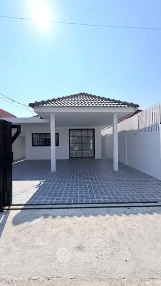 Charming single-story home with tiled roof and spacious driveway under clear blue sky.