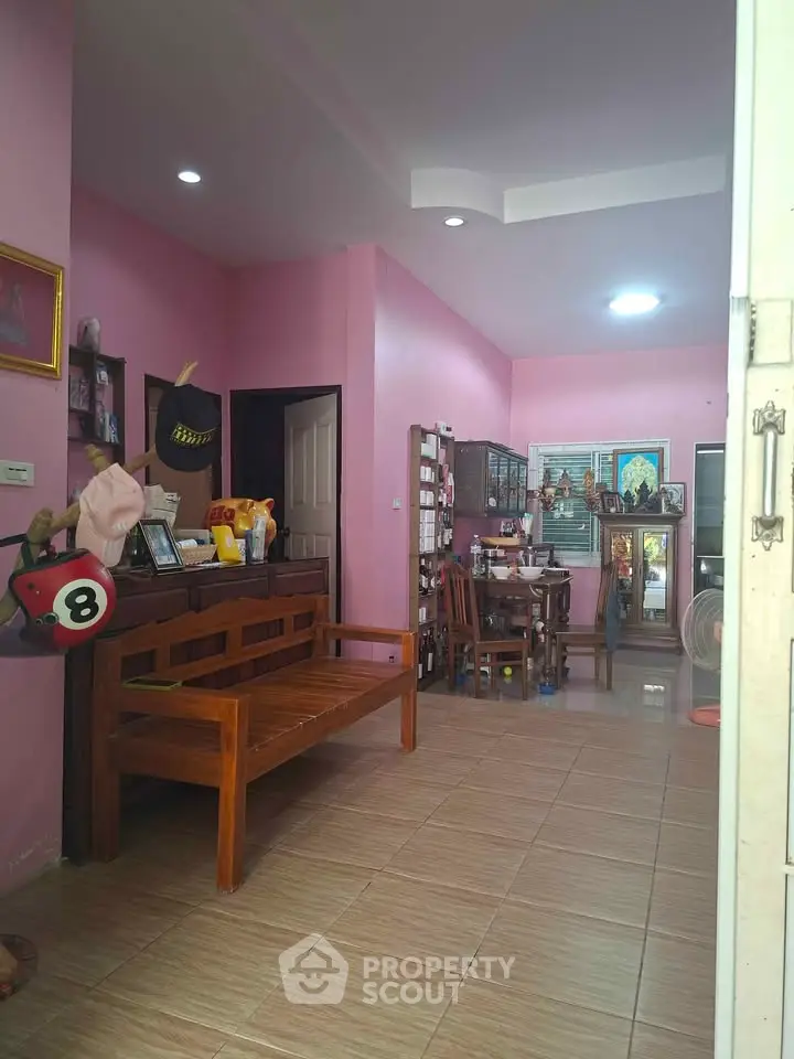 Charming living room with pink walls, wooden furniture, and cozy decor in a welcoming home.