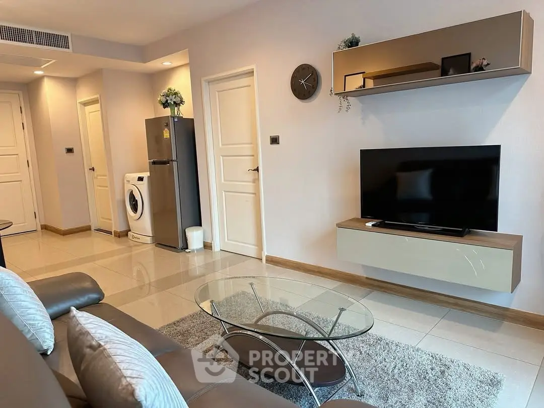 Modern living room with sleek TV setup and washing machine in stylish apartment.