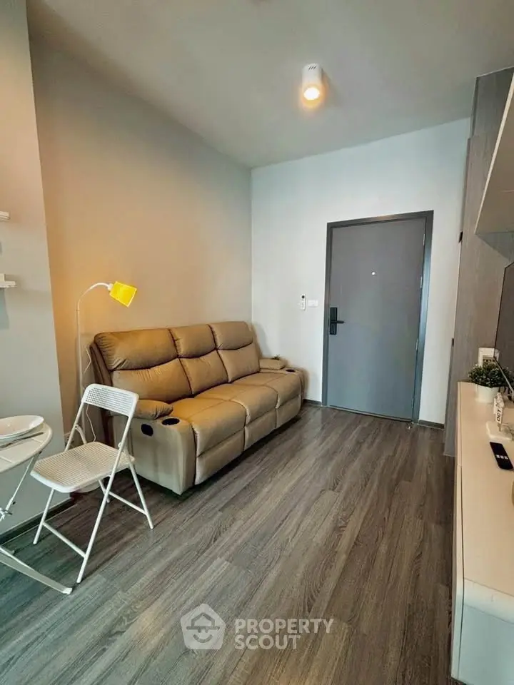 Modern living room with sleek flooring and cozy seating in a stylish apartment.