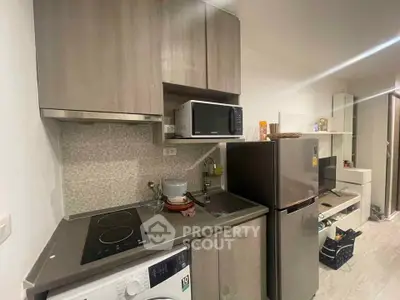 Modern kitchen with sleek cabinets, induction cooktop, and stainless steel appliances in a stylish apartment.