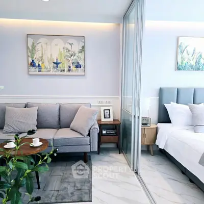 Modern living room with cozy sofa and stylish decor next to a chic bedroom.