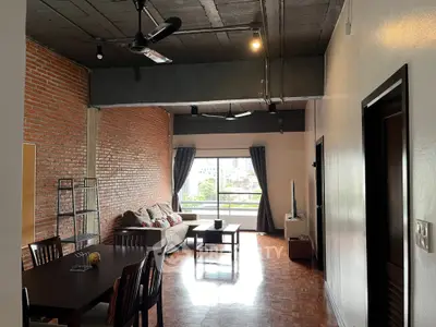Spacious industrial-style living room with brick wall and large window view.