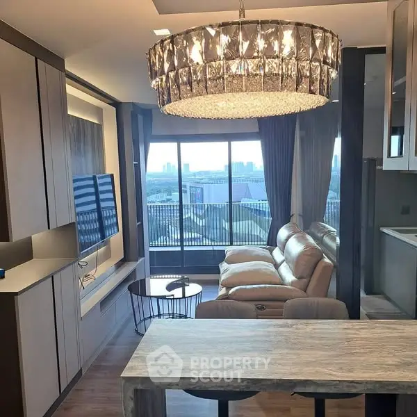 Luxurious living room with stunning chandelier and city view, featuring modern decor and comfortable seating.
