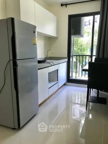 Modern kitchen with sleek appliances and balcony view in a stylish apartment.