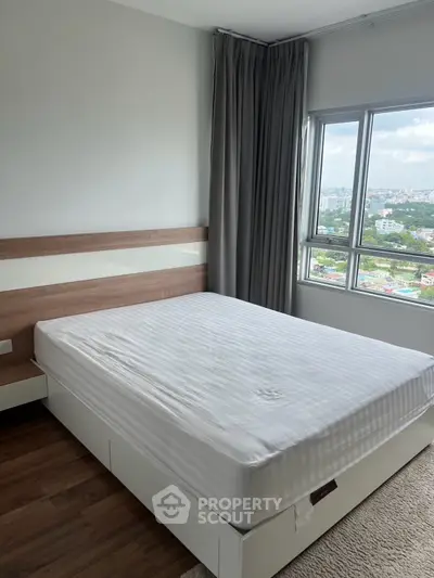Spacious bedroom with large window offering stunning city views, featuring modern decor and cozy ambiance.