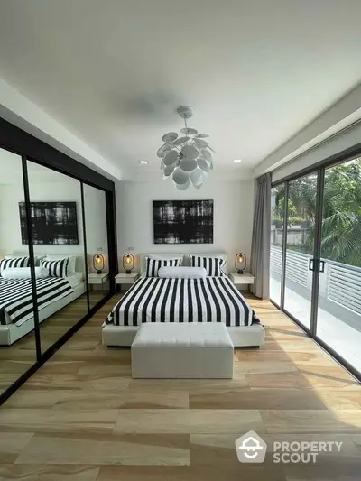 Modern bedroom with striped bedding and mirrored closet doors, featuring a spacious balcony view.