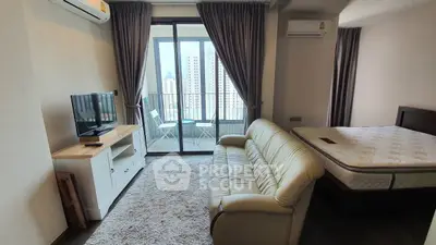 Modern studio apartment with balcony and city view, featuring cozy living area and comfortable bed.
