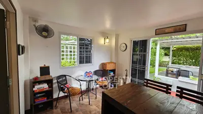 Charming indoor-outdoor living space with garden view and cozy seating area.