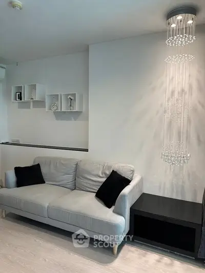 Modern living room with elegant chandelier and cozy sofa, perfect for stylish urban living.