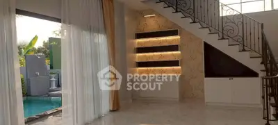 Luxurious living room with elegant staircase and pool view, featuring modern lighting and floor-to-ceiling windows.