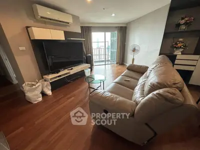 Modern living room with leather sofa and large TV, featuring a balcony view.