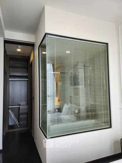 Modern bedroom with glass partition and walk-in closet, showcasing sleek design and contemporary style.