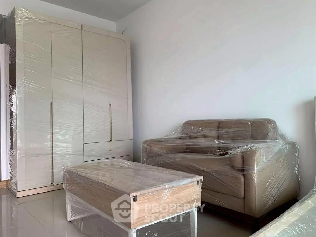 Modern living room with wrapped furniture and sleek wardrobe