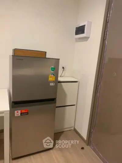 Modern kitchen corner with compact fridge and sleek cabinetry