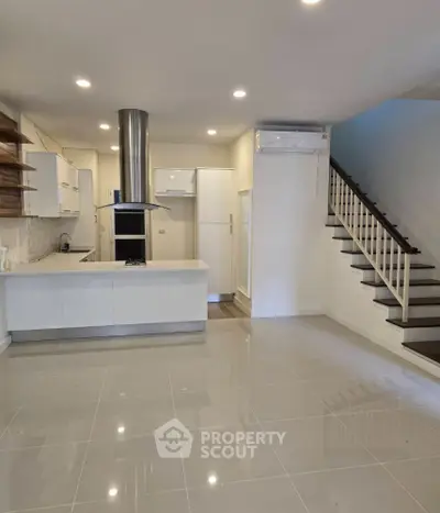 Modern kitchen with sleek design and open layout, featuring stainless steel appliances and stylish staircase.