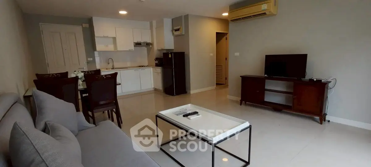 Modern living room with open kitchen and sleek furniture in a cozy apartment.