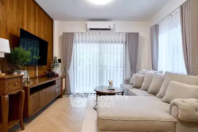 Elegant living room with cozy sectional sofa, wooden accents, and large window draped with sheer curtains.