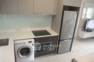 Modern kitchen with sleek appliances including washing machine and fridge, ideal for urban living.