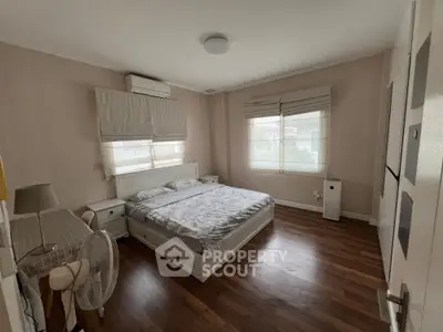 Spacious bedroom with polished hardwood floors, large windows allowing ample natural light, and equipped with modern air conditioning unit.