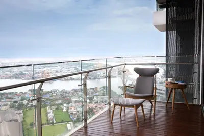 Stunning balcony with panoramic city and river view, featuring modern outdoor seating.
