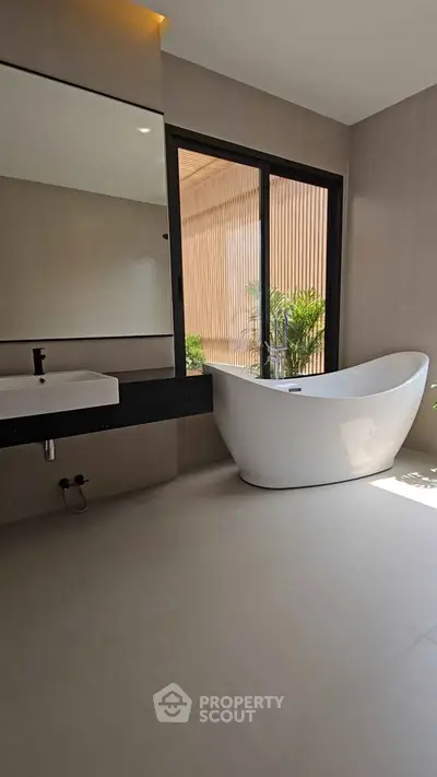 Luxurious bathroom with modern freestanding bathtub and large window view.