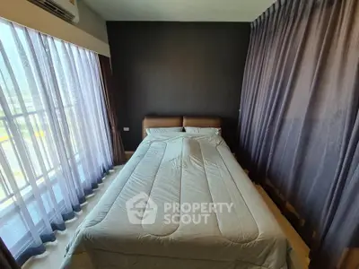 Cozy bedroom with large window and modern curtains, offering ample natural light and a serene atmosphere.