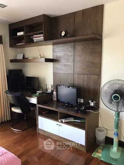 Modern study room with wooden shelves, desk, and dual monitors, perfect for productivity and comfort.