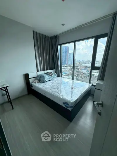 Modern bedroom with large window offering stunning city views in a high-rise apartment.