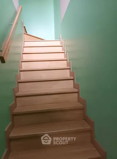 Modern wooden staircase with green walls in a residential property
