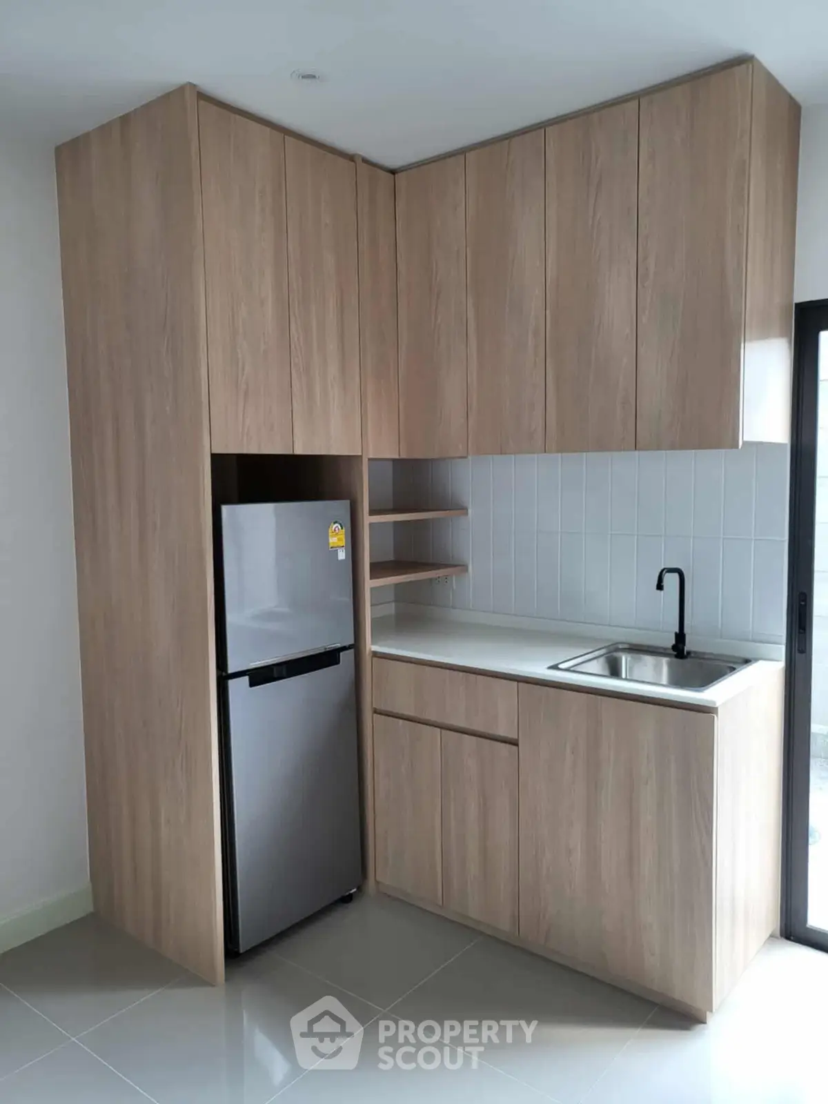 Modern compact kitchen with sleek wooden cabinets and stainless steel fridge