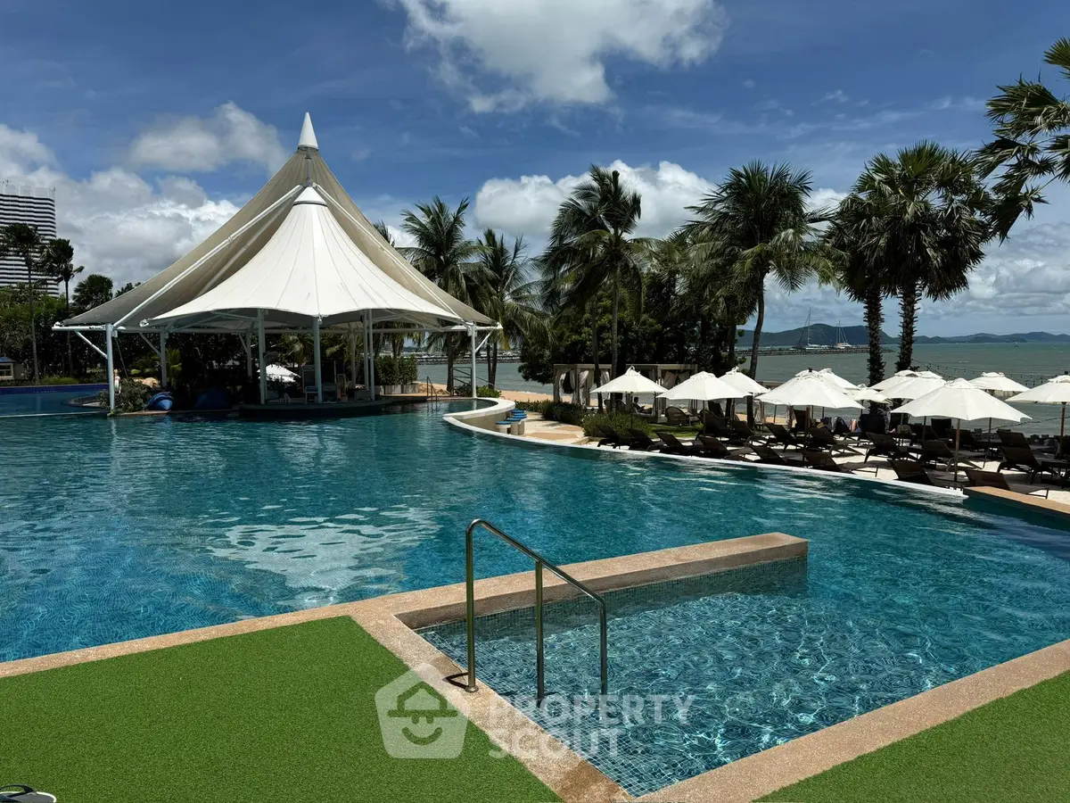 Luxurious beachfront pool with palm trees and elegant canopy, perfect for relaxation and leisure.