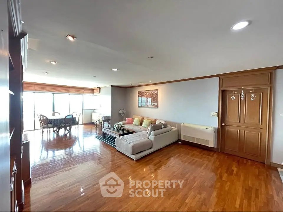 Spacious living room with elegant wooden flooring and cozy seating area, perfect for family gatherings.