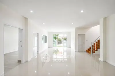 Spacious open-plan living area with glossy tiled floors and staircase in modern home.