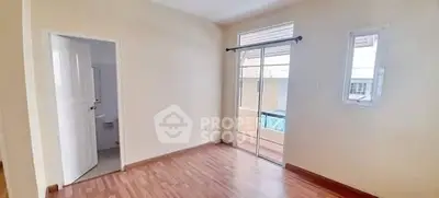 Spacious bedroom with wooden flooring and balcony access in modern apartment.