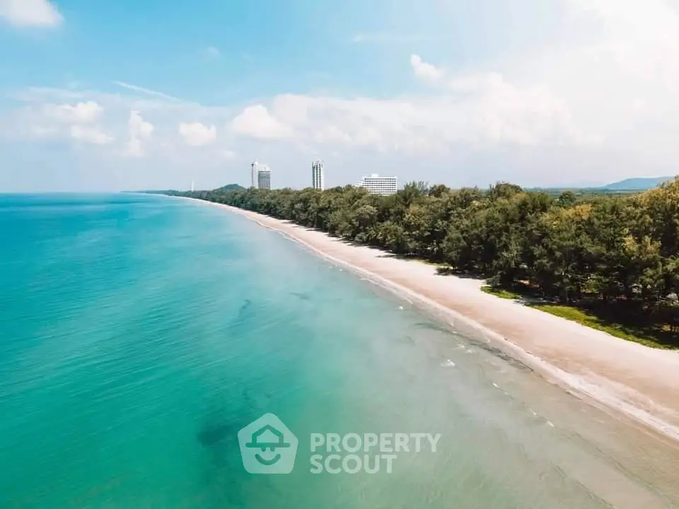 Stunning beachfront view with turquoise waters and lush greenery, perfect for luxury real estate development.
