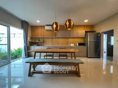 Spacious modern kitchen with wooden accents and large dining area, featuring sleek appliances and natural light.