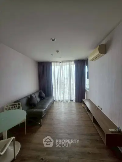 Modern living room with sleek furniture and large window offering natural light.