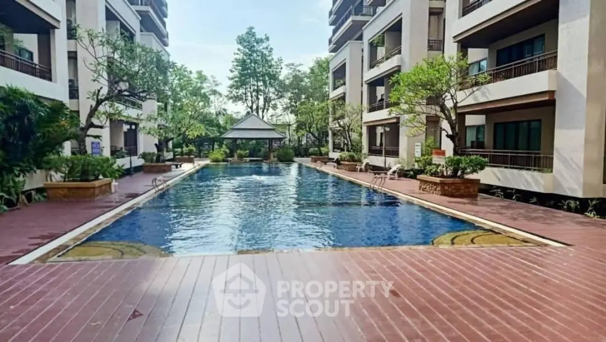 Luxurious apartment complex with serene pool and lush greenery, perfect for relaxation and leisure.