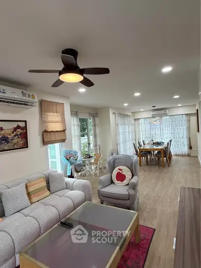 Spacious living room with modern decor and dining area, featuring elegant furniture and natural light.