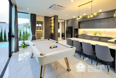 Luxurious open-plan living area with pool table and modern kitchen overlooking a private pool.