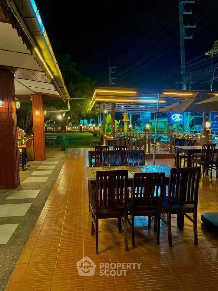 Charming outdoor dining area with ambient lighting and wooden furniture, perfect for evening gatherings.