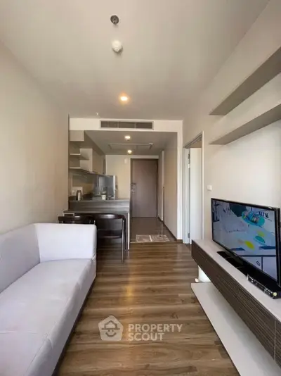 Modern living room with open kitchen, sleek furniture, and wooden flooring in a stylish apartment.