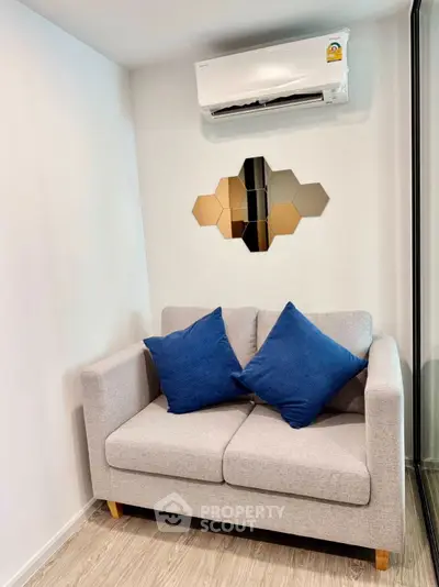 Cozy living room with modern sofa and air conditioning, perfect for relaxation.