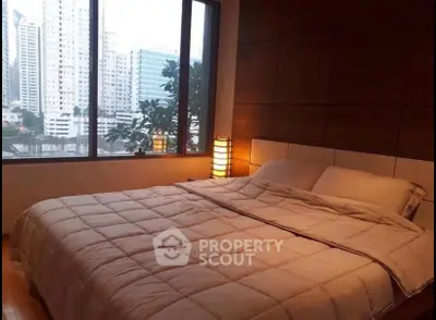 Luxurious bedroom with city view, featuring a cozy bed and elegant decor in a high-rise apartment.